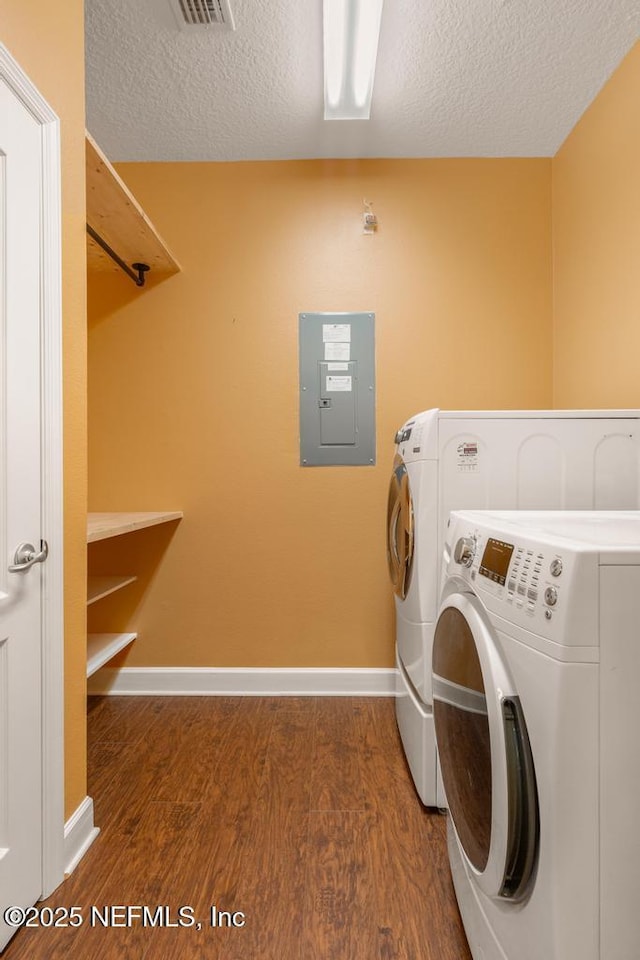 laundry area with washing machine and clothes dryer, a textured ceiling, electric panel, and dark hardwood / wood-style flooring