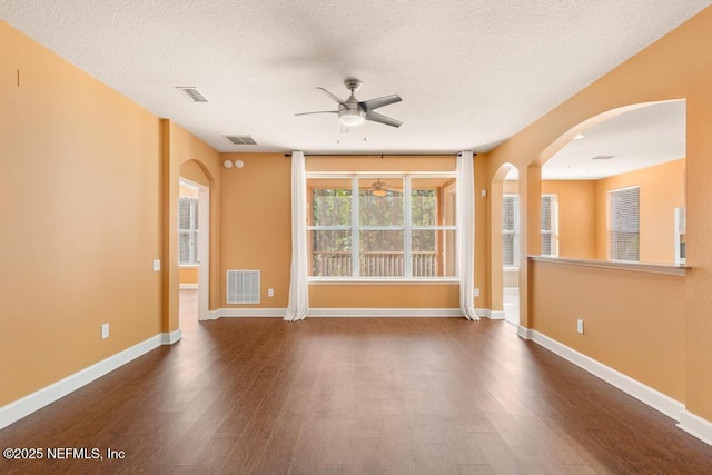 empty room featuring a textured ceiling, dark wood-type flooring, and ceiling fan