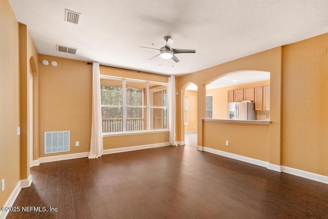 spare room featuring a textured ceiling, dark wood-type flooring, and ceiling fan