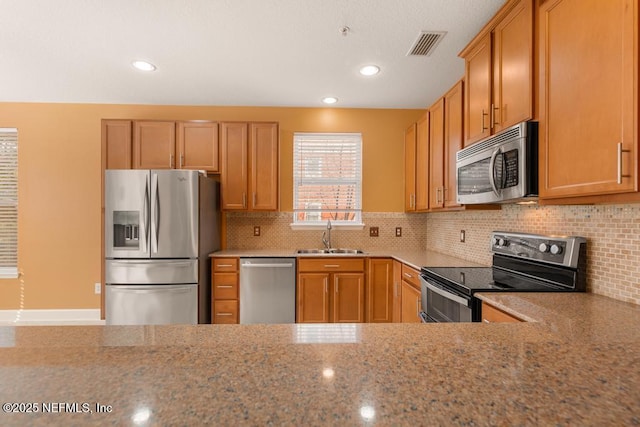 kitchen with tasteful backsplash, stainless steel appliances, light stone countertops, and sink