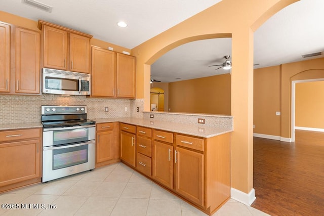 kitchen featuring stainless steel appliances, tasteful backsplash, ceiling fan, and kitchen peninsula