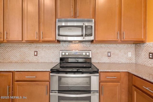 kitchen featuring tasteful backsplash, light stone countertops, and stainless steel appliances