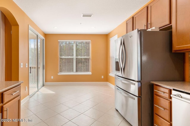 kitchen featuring white dishwasher, light tile patterned flooring, and stainless steel refrigerator with ice dispenser