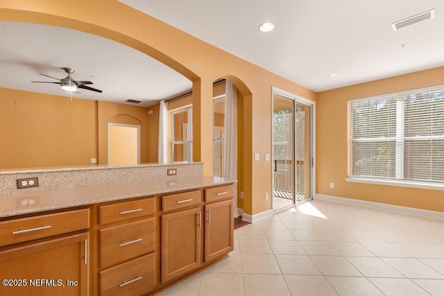 kitchen featuring light stone countertops, light tile patterned floors, and ceiling fan