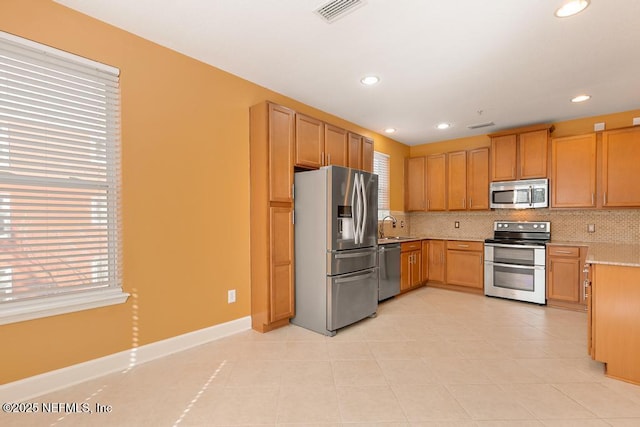 kitchen with sink, decorative backsplash, light tile patterned flooring, and appliances with stainless steel finishes