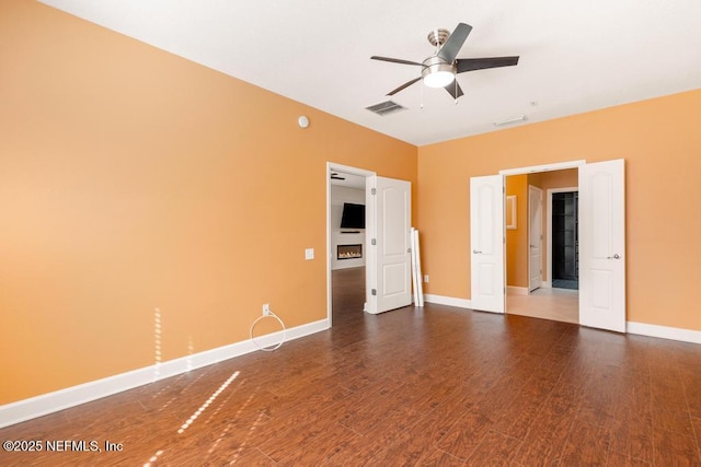 empty room with dark wood-type flooring and ceiling fan