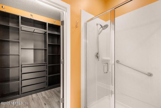 bathroom with wood-type flooring, a shower with door, and a textured ceiling