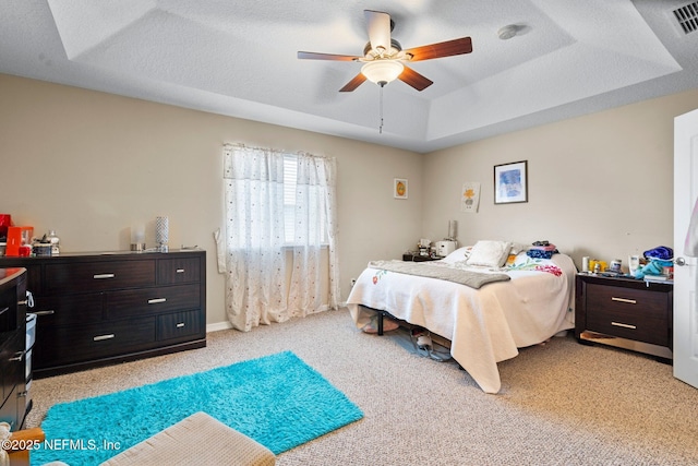 carpeted bedroom featuring a tray ceiling, a textured ceiling, and ceiling fan