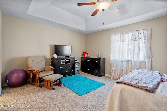 carpeted bedroom featuring a textured ceiling, ceiling fan, and a tray ceiling