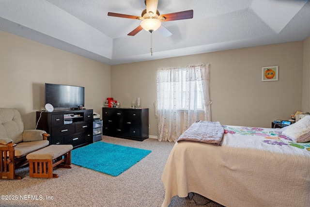 bedroom with light colored carpet, a textured ceiling, ceiling fan, and a tray ceiling