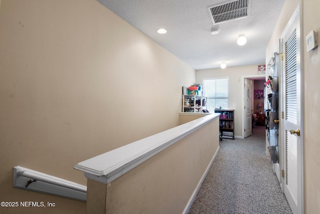 corridor with light colored carpet and a textured ceiling