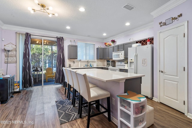 kitchen with crown molding, white appliances, gray cabinets, and a center island