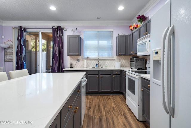 kitchen with sink, crown molding, white appliances, dark hardwood / wood-style floors, and tasteful backsplash