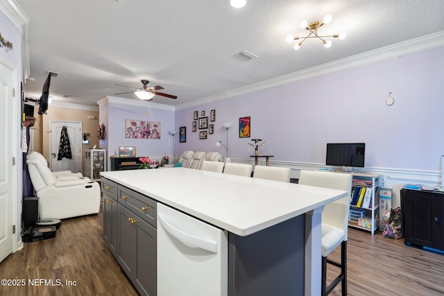 kitchen with gray cabinetry, a center island, ornamental molding, a textured ceiling, and dark hardwood / wood-style flooring