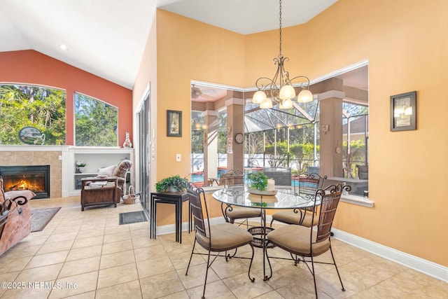 dining room featuring lofted ceiling, light tile patterned floors, a tiled fireplace, built in shelves, and a chandelier