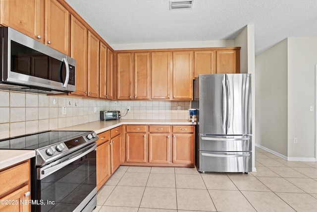 2360 Golfview Dr, Fleming Island, FL 32003 - kitchen featuring appliances with stainless steel finishes, light countertops, tasteful backsplash, light tile patterned floors, and brown cabinetry