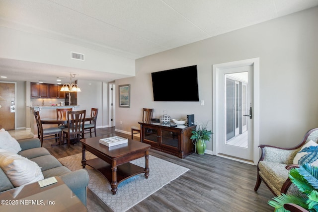 living room with dark wood-type flooring and a notable chandelier