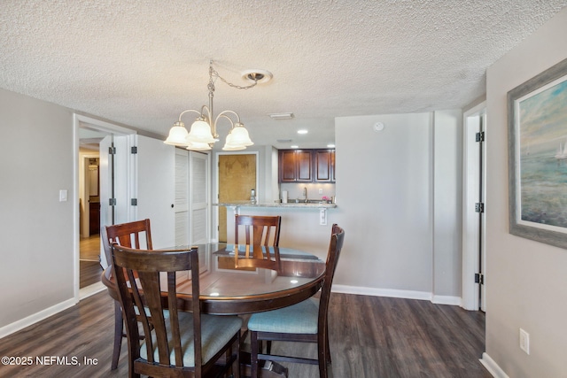 dining area featuring dark hardwood / wood-style floors, sink, a textured ceiling, and a notable chandelier