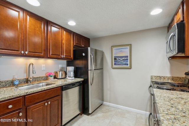 kitchen featuring sink, light tile patterned floors, appliances with stainless steel finishes, light stone countertops, and a textured ceiling