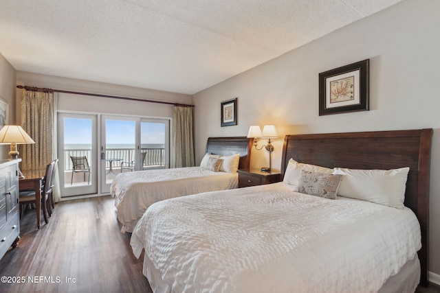 bedroom with a water view, dark hardwood / wood-style floors, a textured ceiling, and access to outside