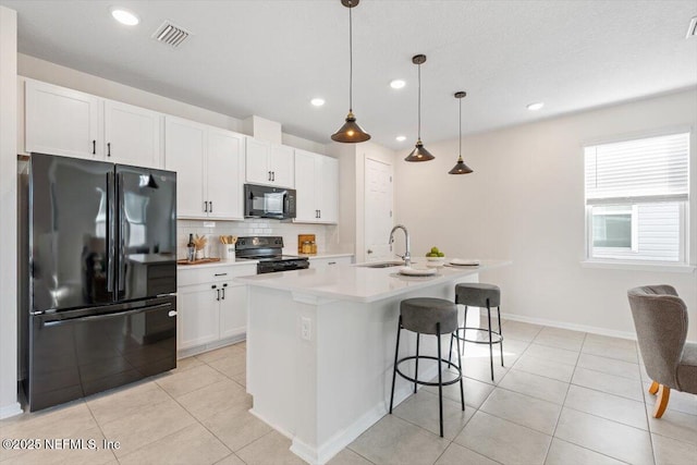 kitchen featuring sink, white cabinetry, a center island with sink, pendant lighting, and black appliances