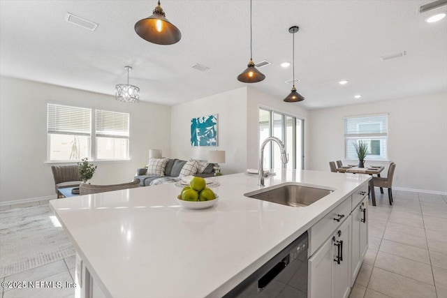 kitchen featuring sink, black dishwasher, an island with sink, pendant lighting, and white cabinets