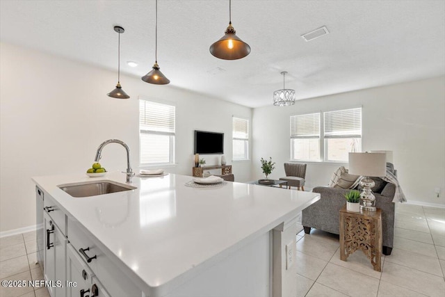 kitchen with pendant lighting, white cabinetry, an island with sink, sink, and light tile patterned floors