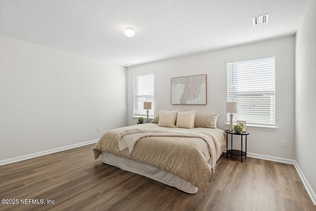 bedroom with multiple windows and hardwood / wood-style flooring