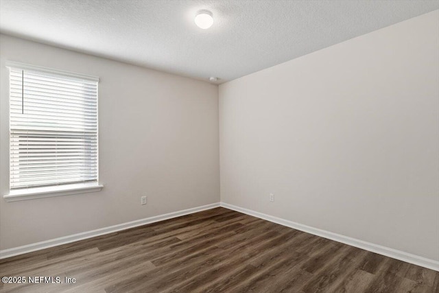 empty room featuring plenty of natural light, a textured ceiling, and dark hardwood / wood-style flooring