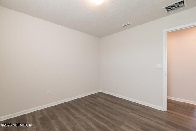 unfurnished room featuring dark wood-type flooring and a textured ceiling