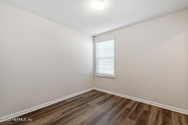 unfurnished room with dark wood-type flooring and a textured ceiling