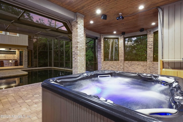 view of patio featuring glass enclosure and a hot tub