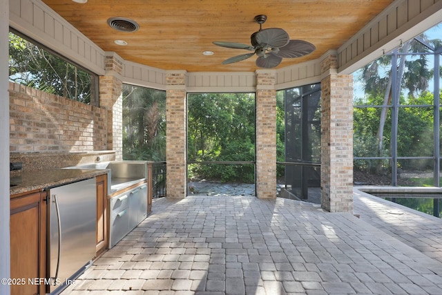 view of patio / terrace with glass enclosure, area for grilling, a ceiling fan, and visible vents