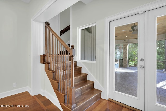 stairs with baseboards, wood finished floors, and a ceiling fan