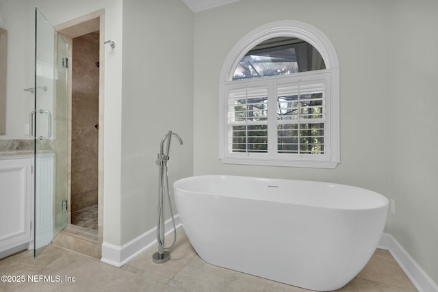 full bath featuring tile patterned flooring, a shower stall, baseboards, and a freestanding bath