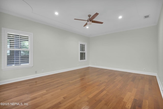 empty room with wood finished floors, baseboards, visible vents, ornamental molding, and ceiling fan