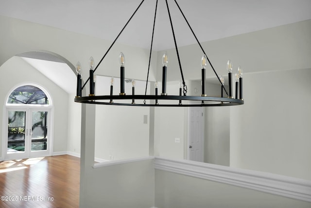 interior space with lofted ceiling, wood finished floors, arched walkways, and baseboards