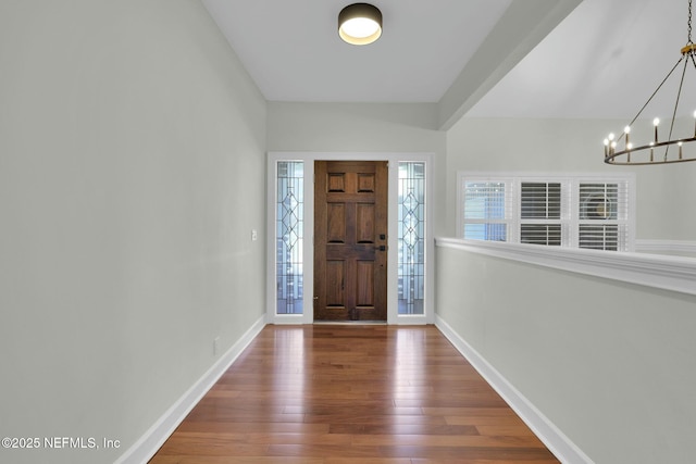 entryway featuring baseboards, a notable chandelier, and hardwood / wood-style floors