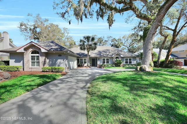 single story home featuring an attached garage, concrete driveway, brick siding, and a front yard