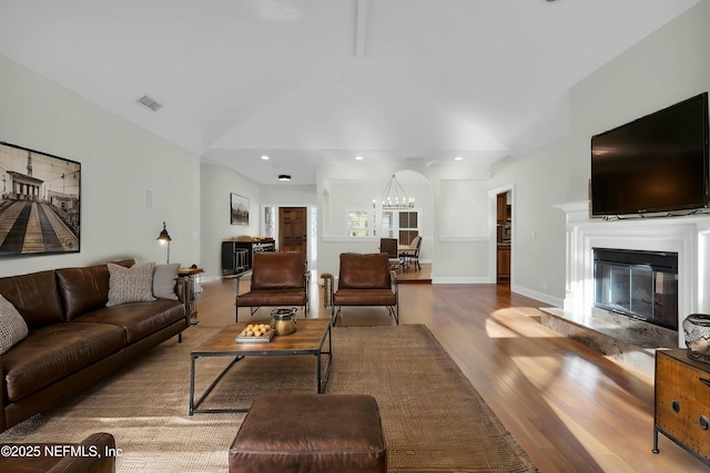 living room with high vaulted ceiling, baseboards, visible vents, a high end fireplace, and wood finished floors