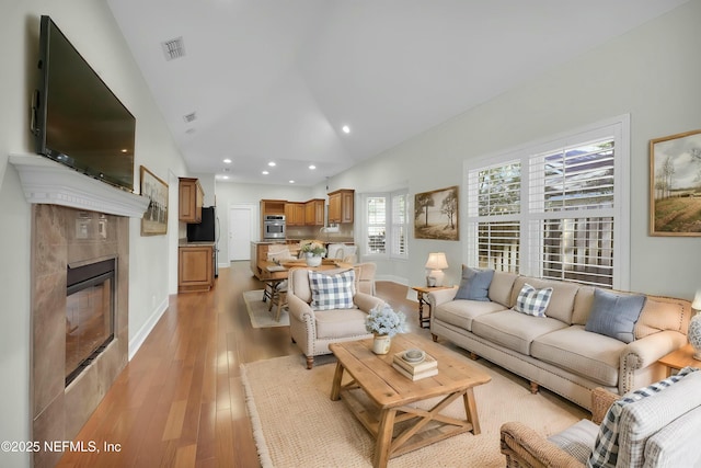 living room featuring recessed lighting, baseboards, light wood-style floors, visible vents, and a tiled fireplace