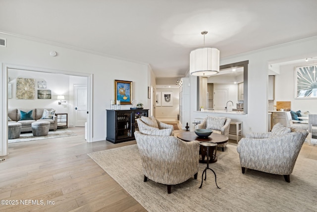 living room with ornamental molding and light wood-type flooring