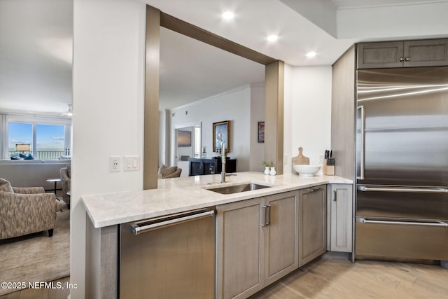 kitchen with sink, light hardwood / wood-style flooring, kitchen peninsula, stainless steel appliances, and light stone countertops