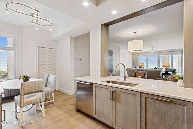 kitchen featuring decorative light fixtures, dishwasher, sink, light stone counters, and light hardwood / wood-style flooring