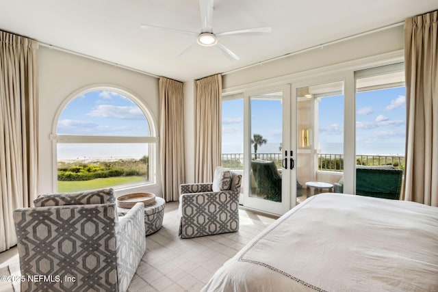 bedroom with multiple windows, access to exterior, ceiling fan, and a water view