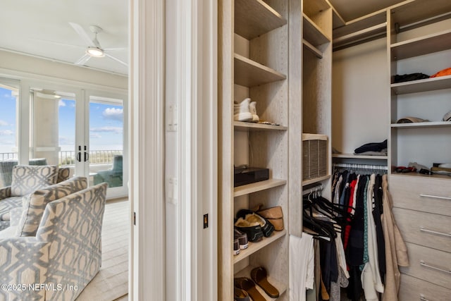 walk in closet with french doors and ceiling fan