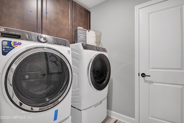 clothes washing area featuring cabinets and washer and dryer