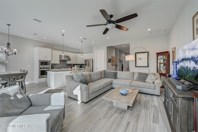 living room with ceiling fan with notable chandelier