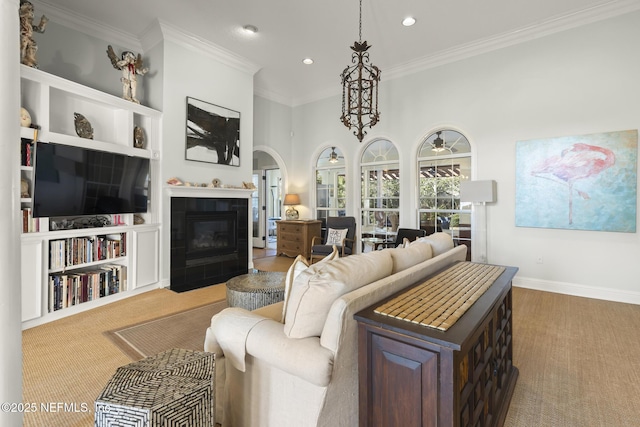 living area with a fireplace, arched walkways, crown molding, and recessed lighting