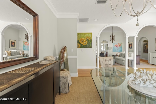 dining room featuring an inviting chandelier, light hardwood / wood-style floors, ornamental molding, and decorative columns